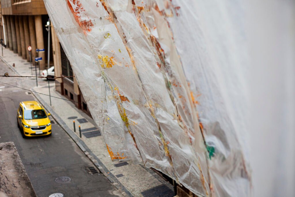 High-angle street photo looking down at a large textile banner hanging from a building facade, by Osmar