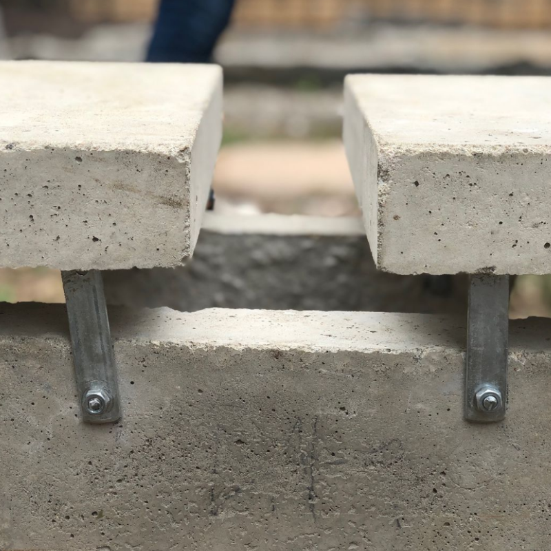 Close-up detail photo of metal brackets clamping two concrete blocks together, furniture prototype by Osmar