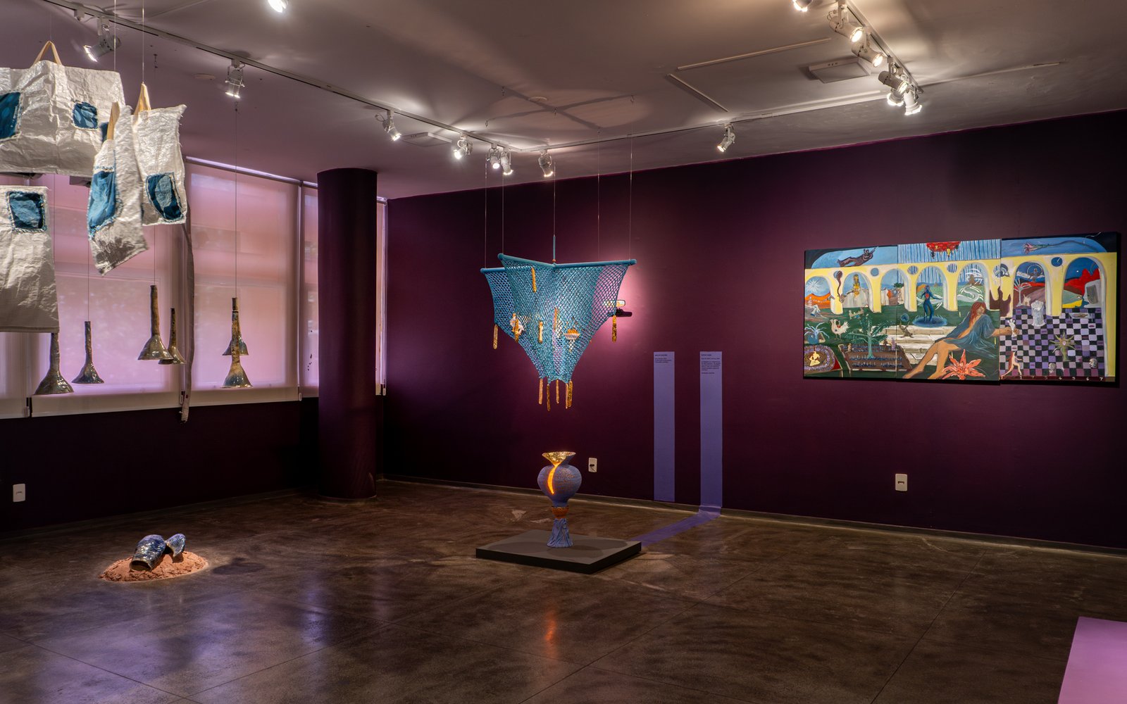 Wide interior view of a moody purple-themed exhibition gallery displaying horizontal artworks, by Osmar
