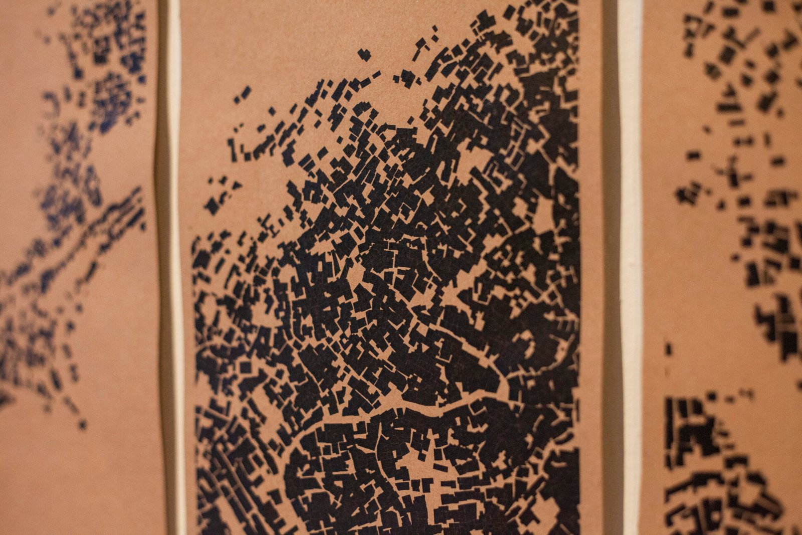 Artistic multi-panel map illustration combining high-density black urban grid layouts on an orange background, by Osmar