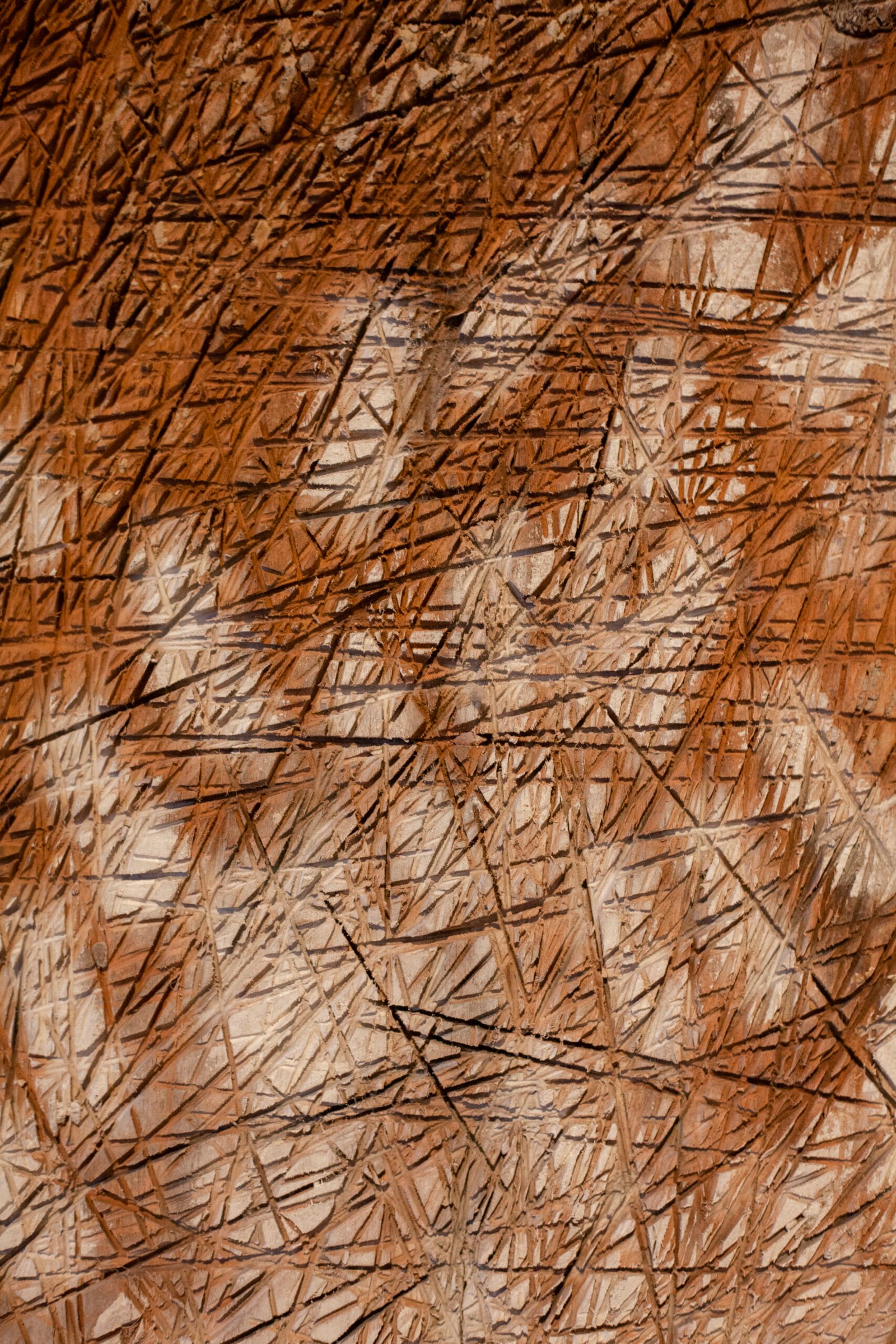 Close-up of a rustic textured panel showing layered vertical scratch-like patterns in warm brown tones, by Osmar