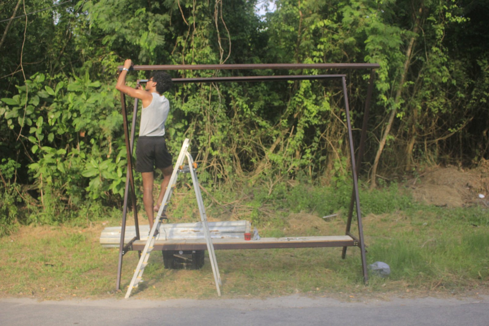 Person standing on top of a simple scaffolding structure built beneath garden foliage, by Osmar