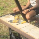 Close-up of hands handling tools and wooden boards on a workbench in Osmar