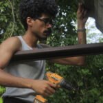 Young man in profile working on a construction site or woodworking workshop, Osmar