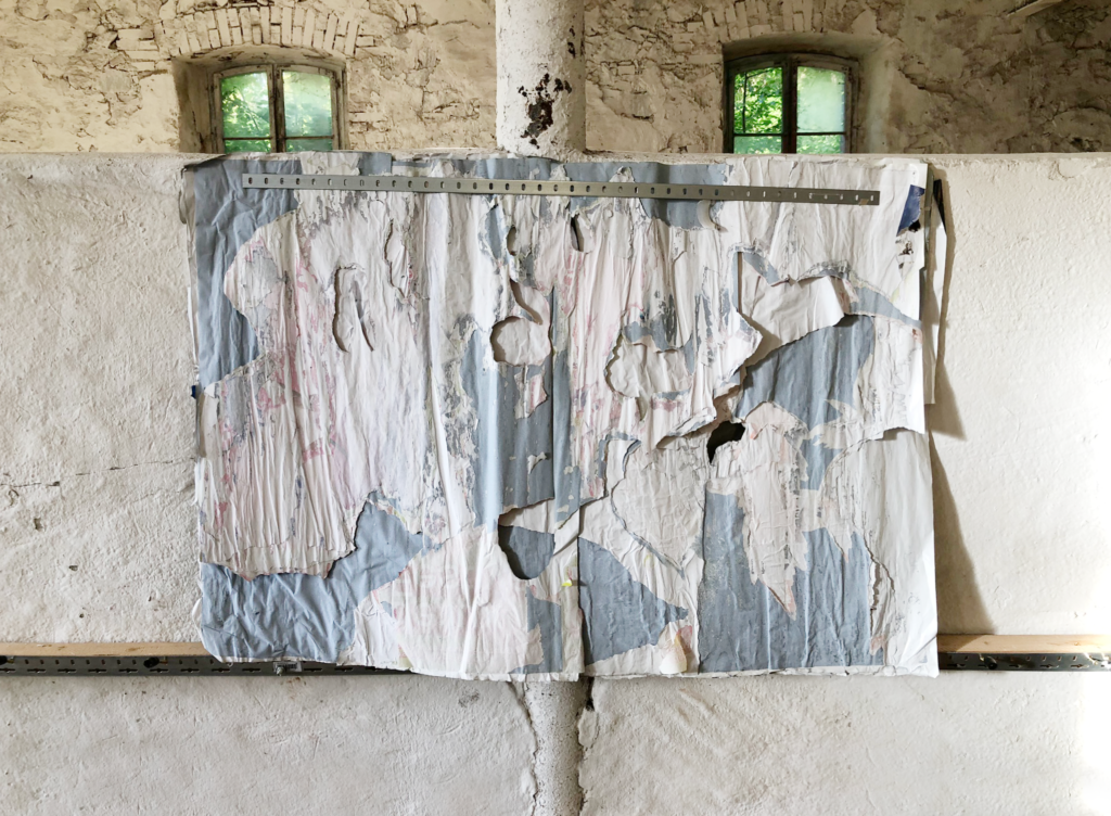 A wide shot of large blue architectural drawings displayed on a wall in a stone workshop. by Osmar